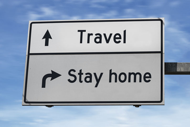 Two signs, one staying Stay home, the other saying Travel