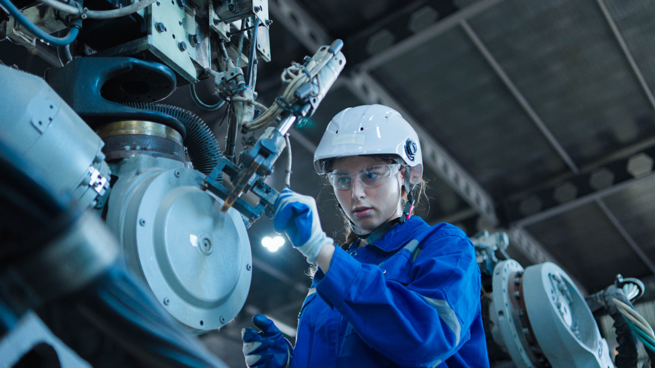 A photo of a female engineer in protective clothing working on a machine