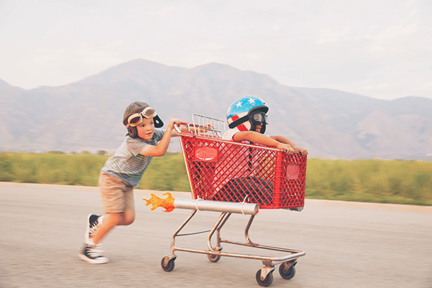 Two children racing in a shopping trolley